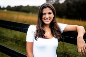 Outdoor senior portrait at rustic farm fence during golden hour.