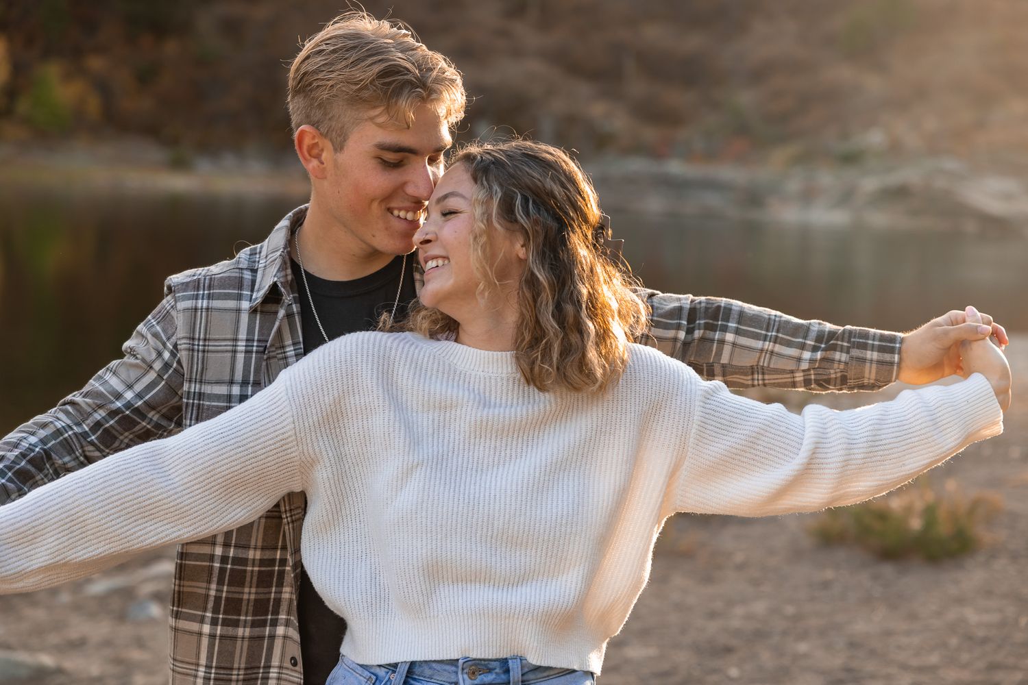Playful romantic moment captured at sunset with sweater-clad couple. Spokane wedding photographer.