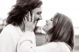 A black and white photo of a couple sharing a tender romantic moment close together.
