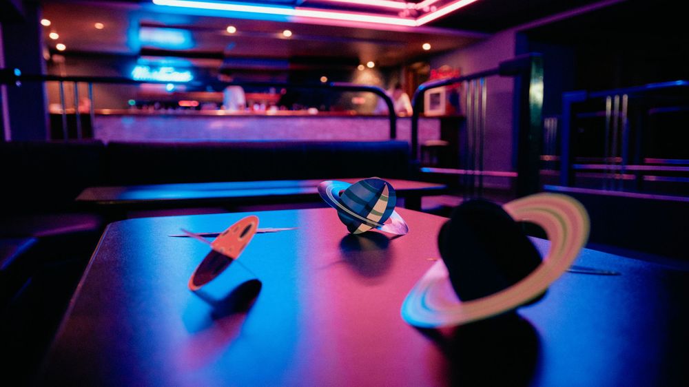 Illuminated ping pong table in a darkened club with moody neon lighting creating an atmospheric nightlife scene.