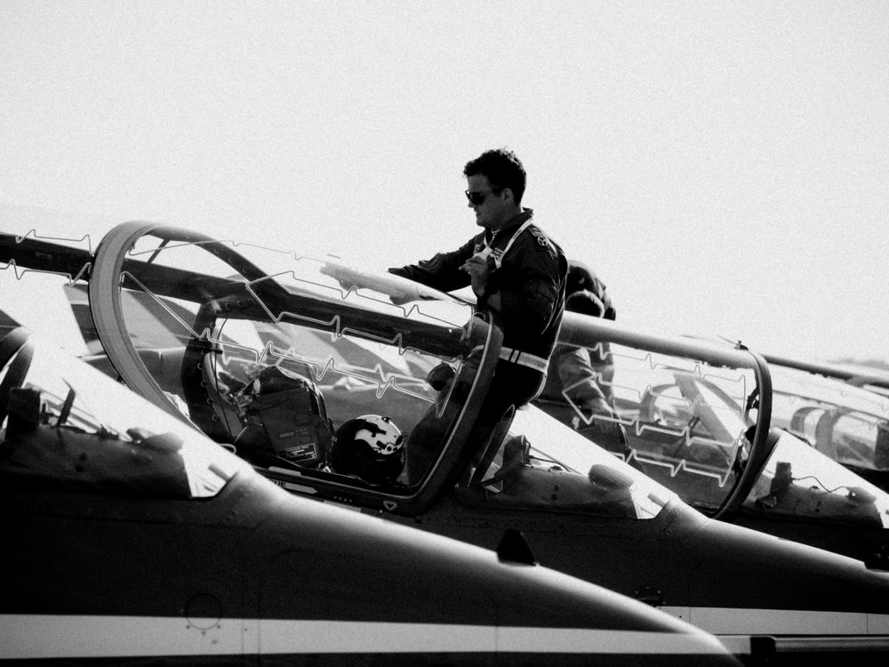 Black and white photo of a pilot preparing in the cockpit of a vintage aircraft.