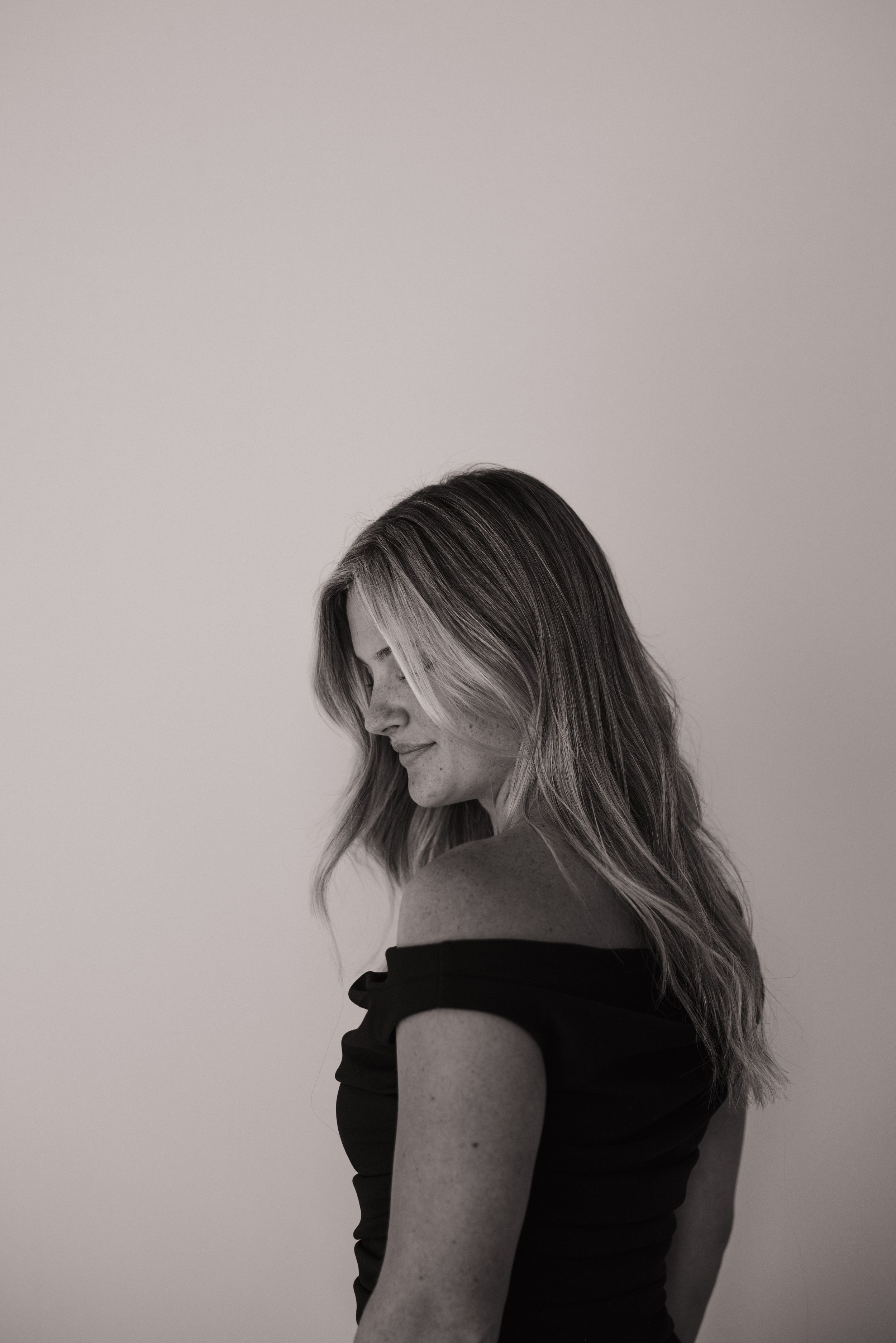 A series of profile portraits in black and white showing someone in a black top against a light background.