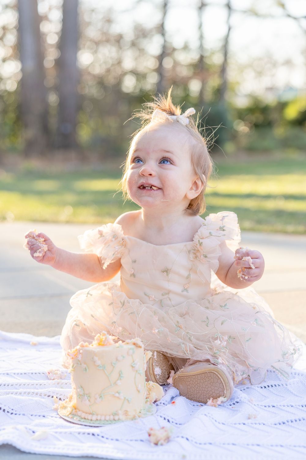 A series of photos showing a baby's first cake smash experience with white frosting and natural outdoor lighting.