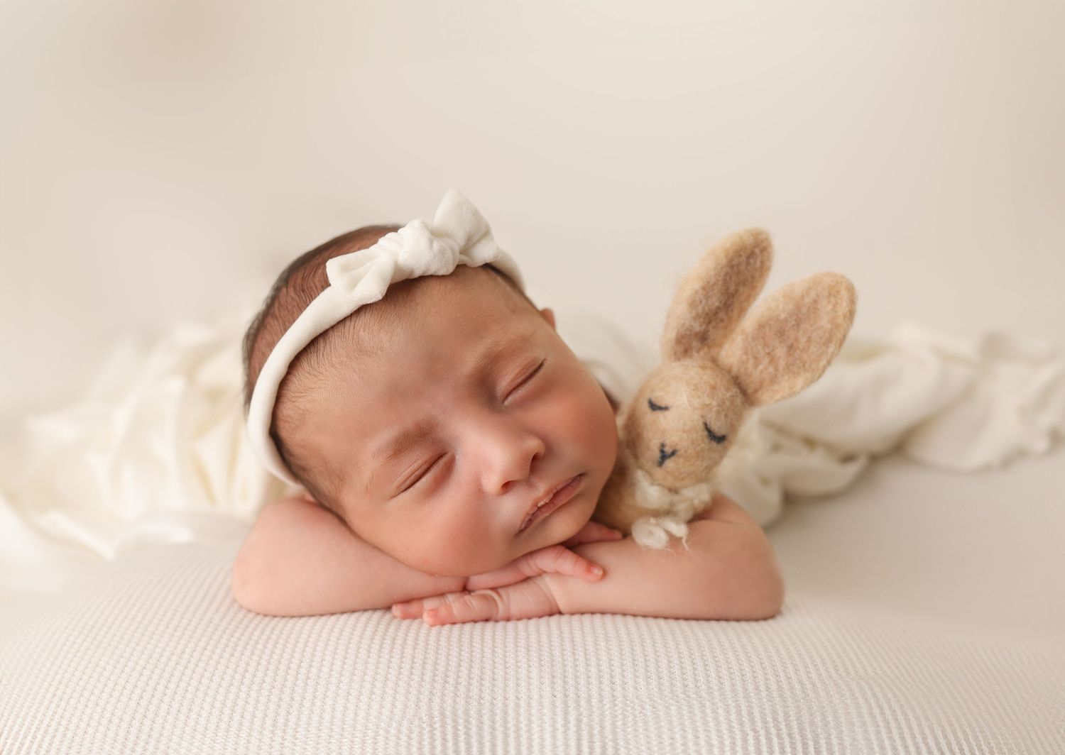 Sleeping newborn wrapped in pink swaddle resting in round basket with flowers.