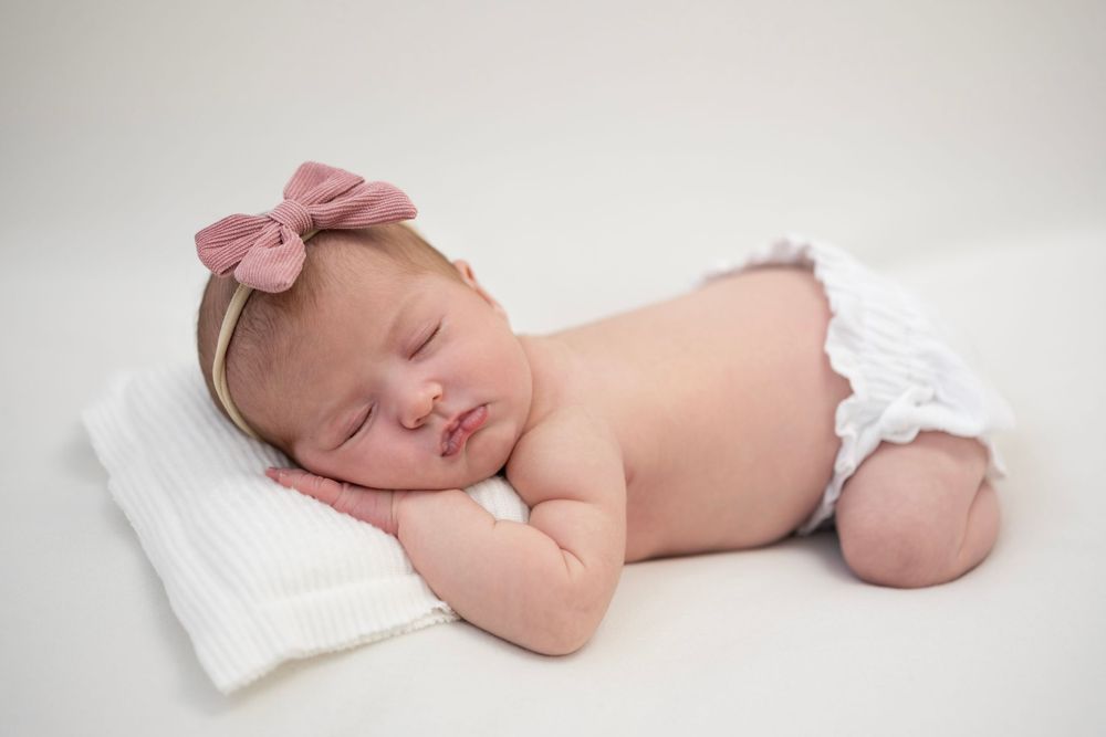 Newborn baby girl lying on her front on a soft pillow during newborn photography session
