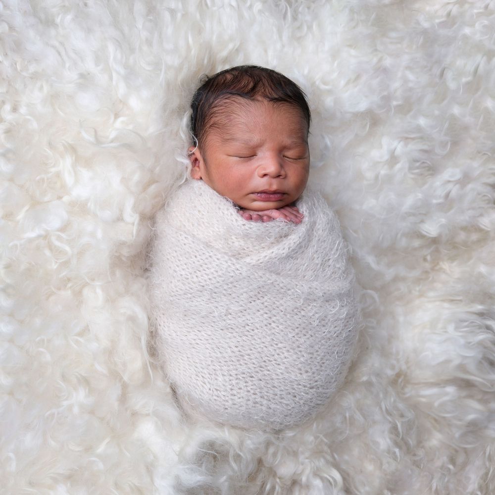 newborn baby wrapped up and on a fluffy background