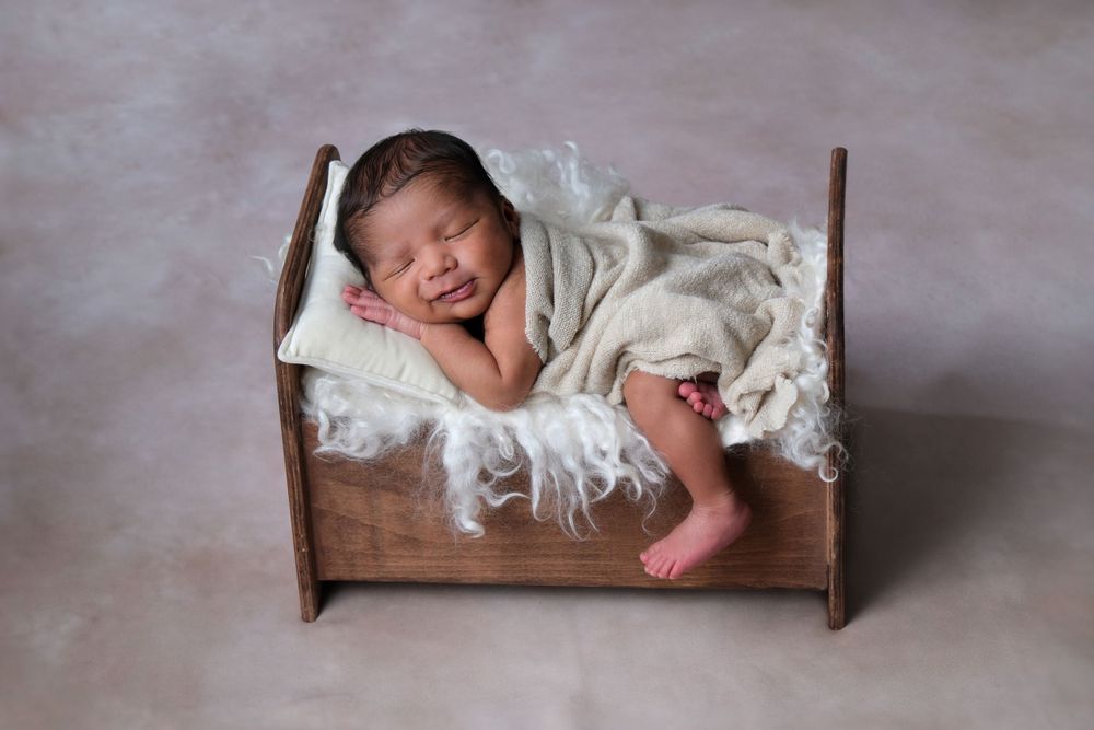 Newborn baby posed on layered bedding during newborn photography session