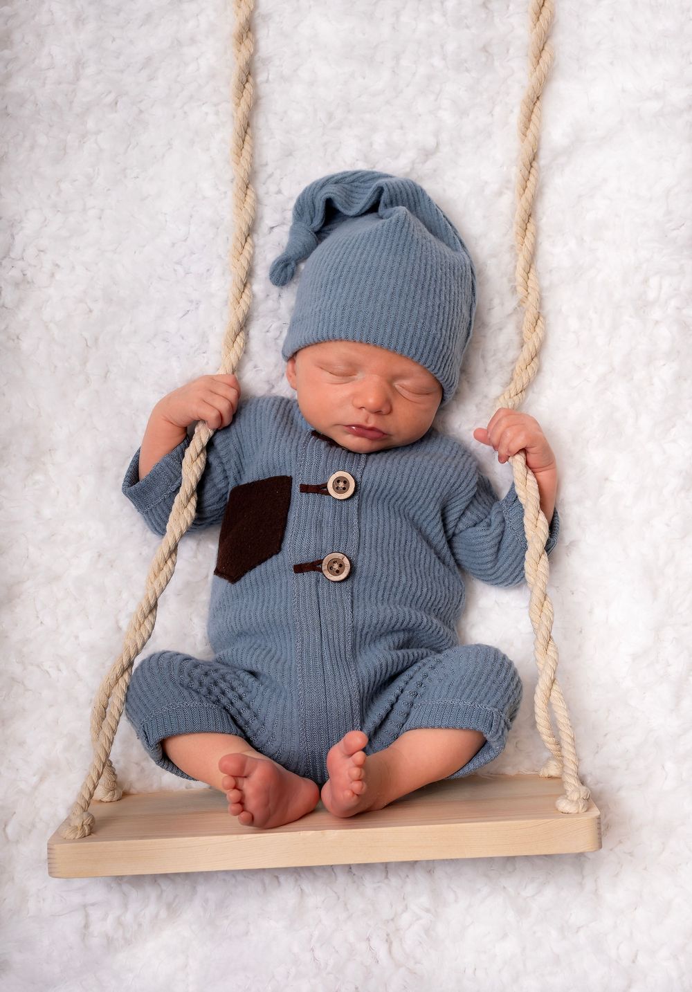 Newborn boy posed on swing prop — newborn photography near Devizes