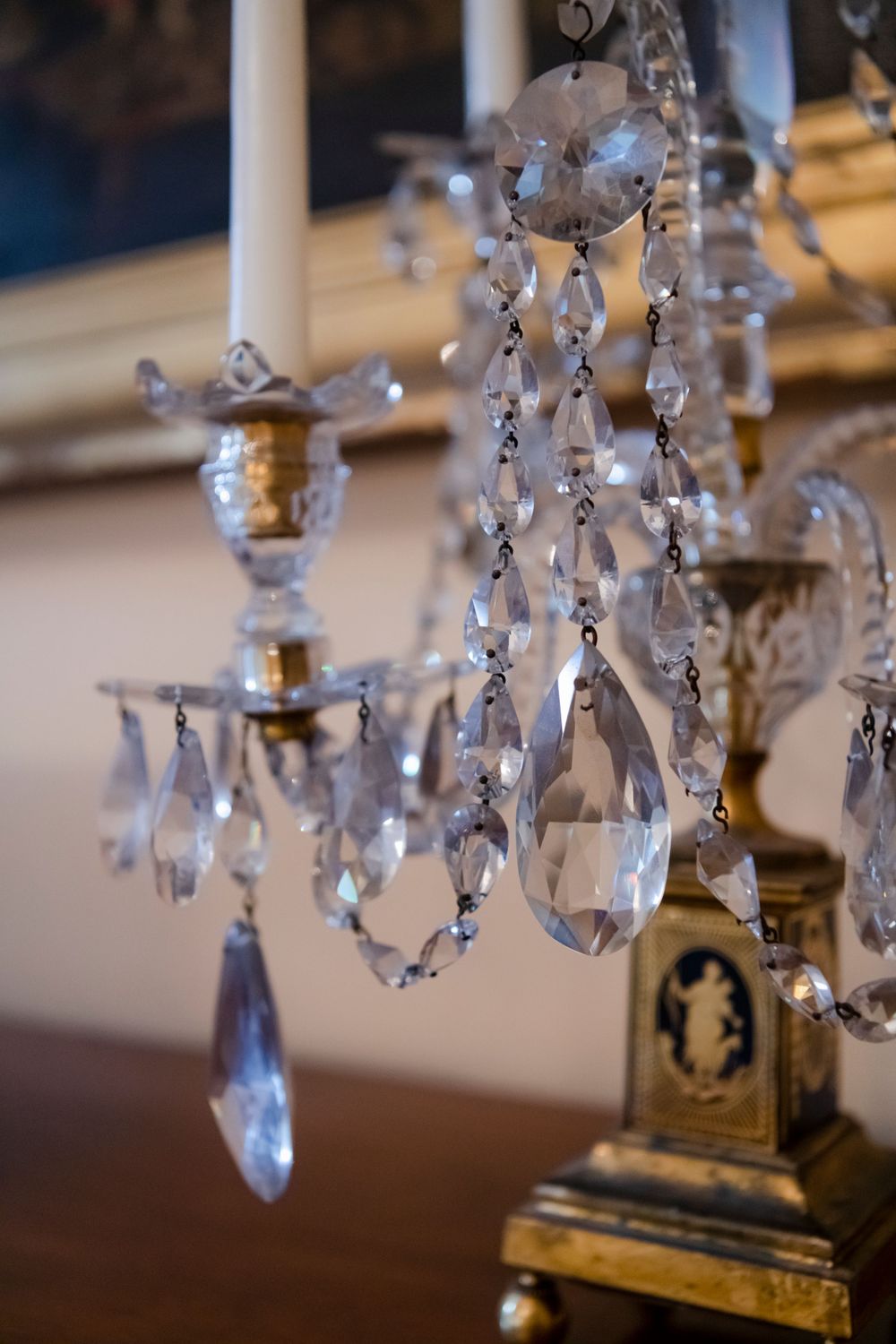 Crystal drops hanging from an ornate vintage chandelier with glass prisms and gold accents catch the light elegantly.