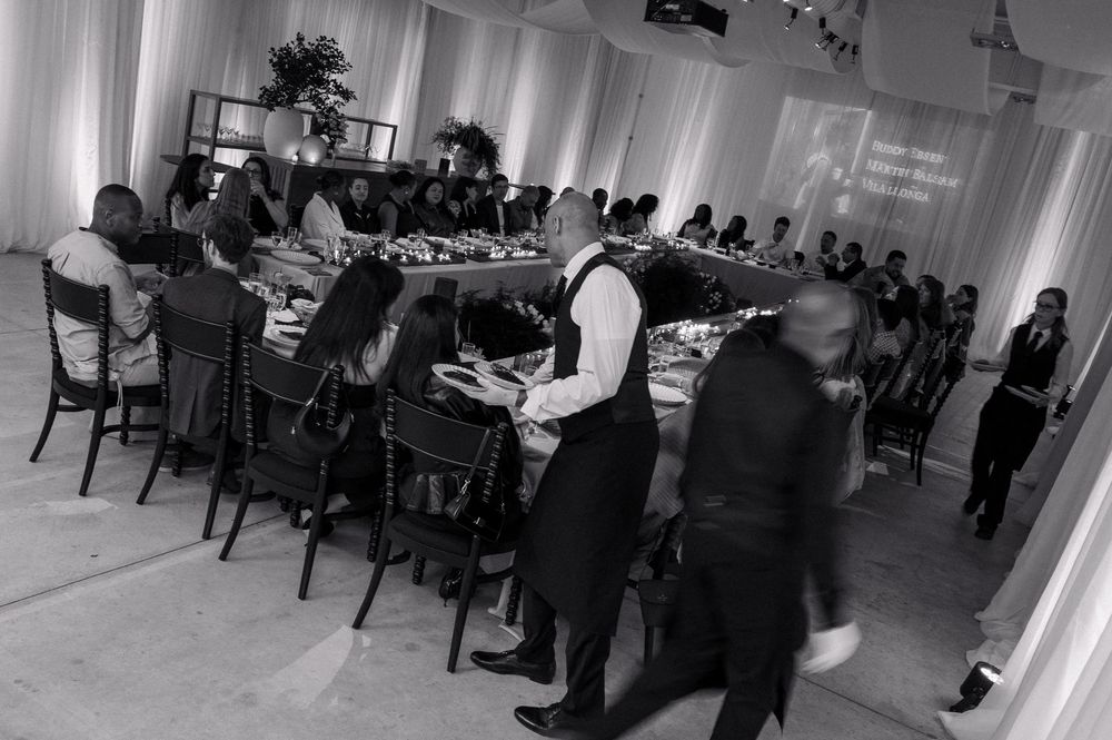 Black and white photo of elegantly dressed guests dining at a long banquet table during a formal event.
