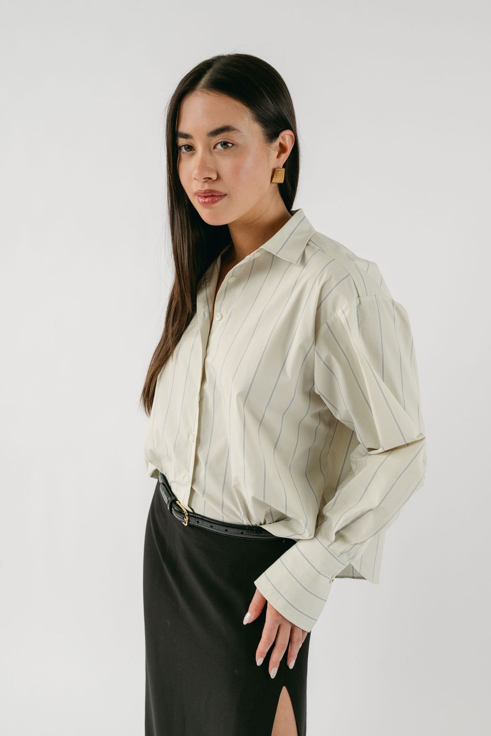 Model showcasing a dramatic white ruffled blouse paired with dark pants against a white background.
