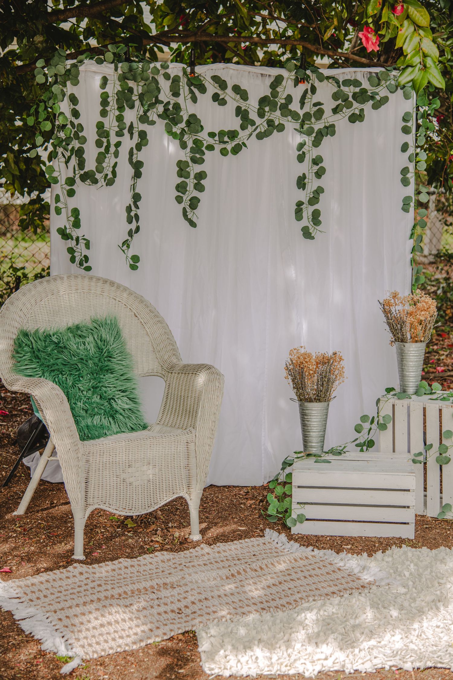 Elegant outdoor seating area with wicker loveseat, floral wall, and coordinated mint green and pink decor.