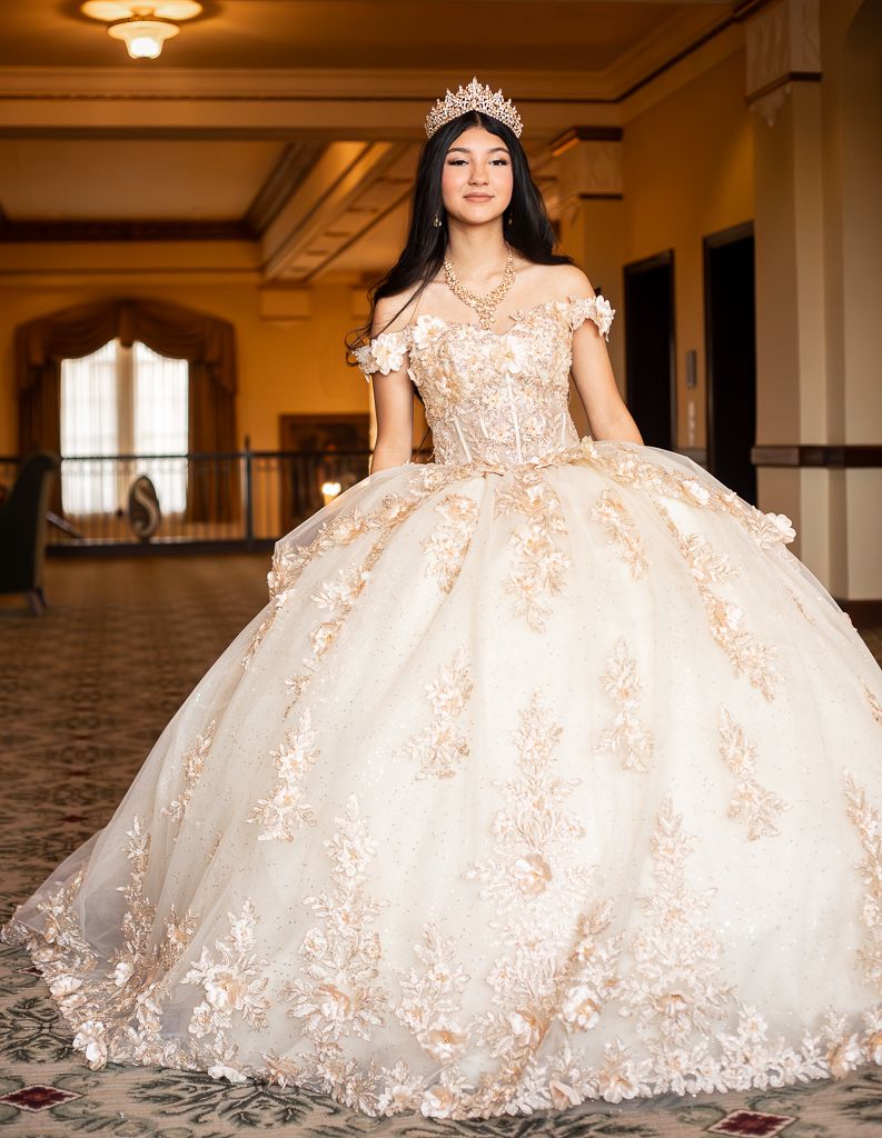Three women posing together, with one wearing a vibrant blue quinceañera gown with silver embellishments.