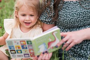 Reading together in nature while sitting in green grass.