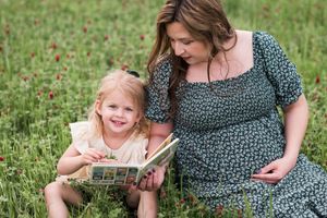 Series of intimate maternity photos showing couple reading together in a grassy meadow.