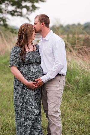 Couple embracing in a rustic field setting wearing coordinated casual outfits.