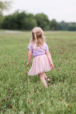 A pink dress swaying in a field of red poppies and tall grass on a summer day.