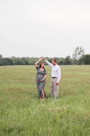 A couple dances together in a serene meadow on a cloudy day.