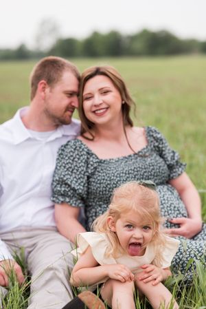 A family shares playful moments together while sitting in a flowering meadow.