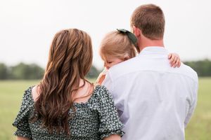 A couple in coordinated outfits embracing while looking at a scenic view in an outdoor setting.