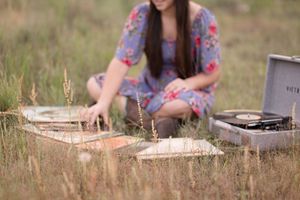 A vintage typewriter sits in tall grass while papers scatter across a meadow.