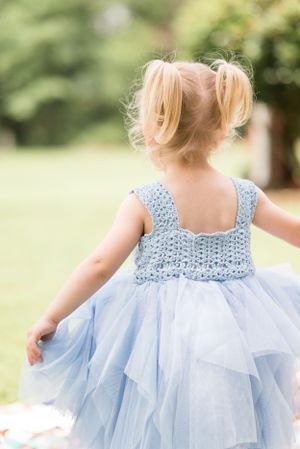 Back view of a light blue tulle dress with detailed crochet bodice in a garden setting.