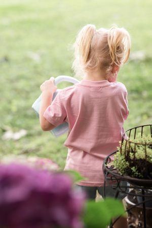 Back view of a child in pink shirt standing in garden.