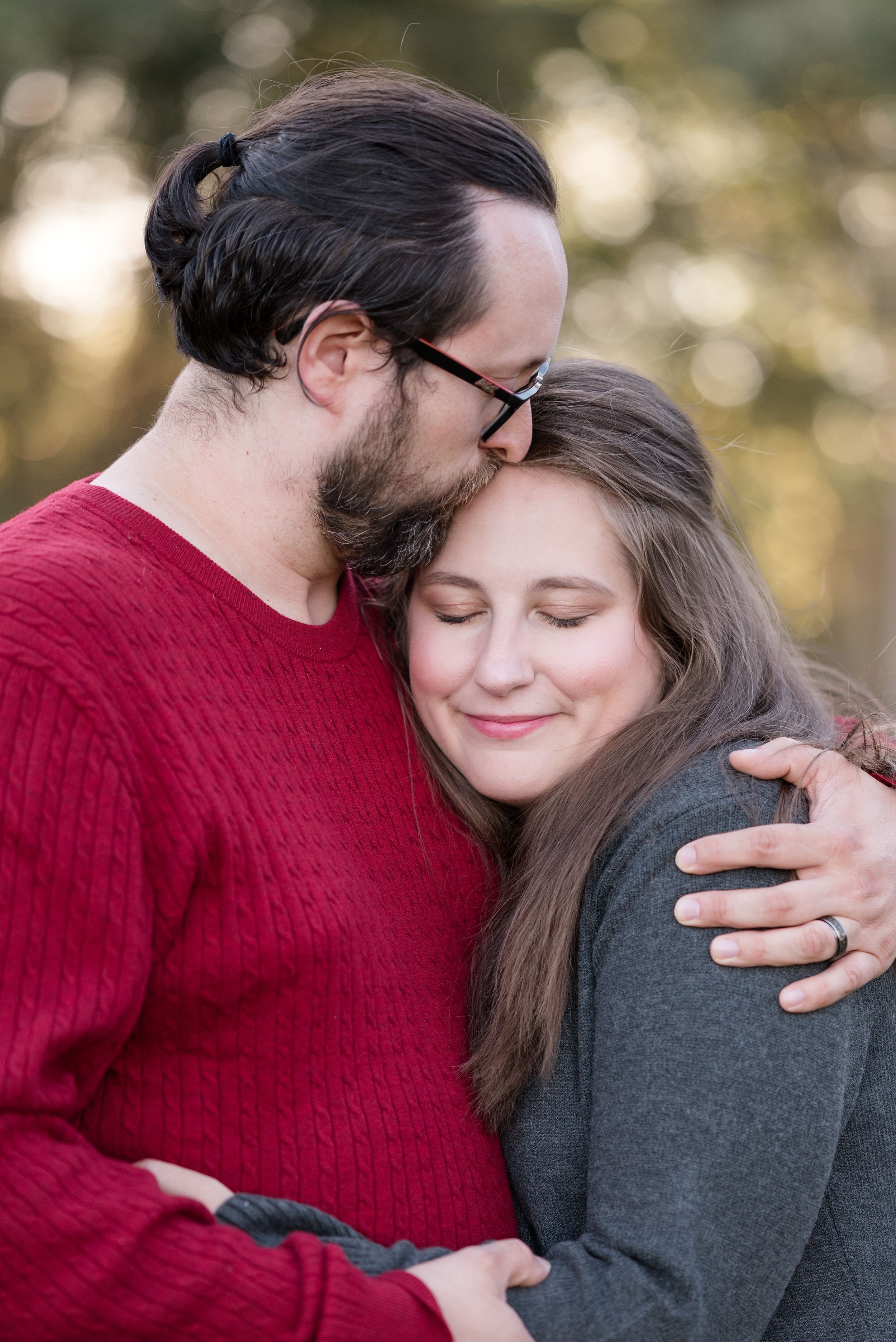 A romantic couple shares tender moments while wearing red and gray sweaters in golden evening light.
