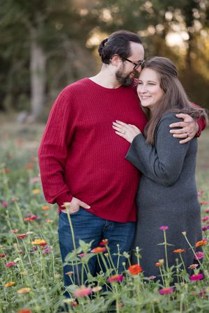 A couple embraces in a field of colorful zinnias during golden hour sunset.