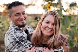 Happy couple laughing together in a garden setting during golden hour.