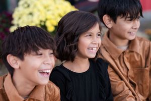 A group of children smile and laugh together during an outdoor gathering.