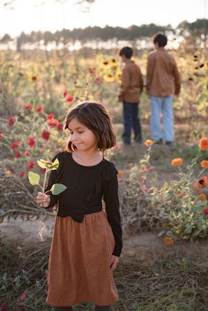 People explore a colorful flower field with blooming poppies and sunflowers on a warm autumn day.