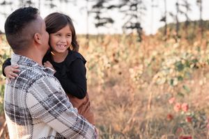 A couple poses together during a golden hour photoshoot in an autumn field setting.