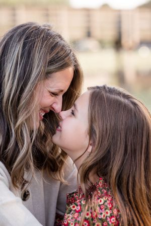 Two people share a tender moment together outdoors with soft lighting and natural background.
