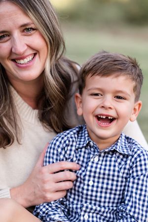 A heartwarming portrait of a parent and young child in a gingham shirt sharing genuine laughter outdoors.