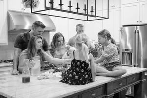 Family gathered around kitchen island sharing casual moments together in black and white.