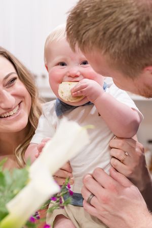 Sweet candid moments of a baby being playfully held and kissed in a bright setting.
