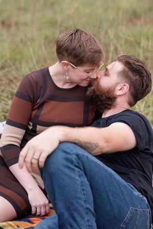 Couple sharing an intimate moment while lying together on grass outdoors.