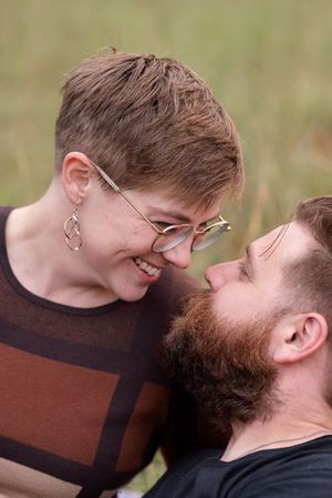 A tender moment captured in close-up showing affection between two people wearing glasses and a brown sweater.