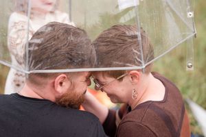 A couple shares a romantic kiss while standing outdoors in a natural setting.