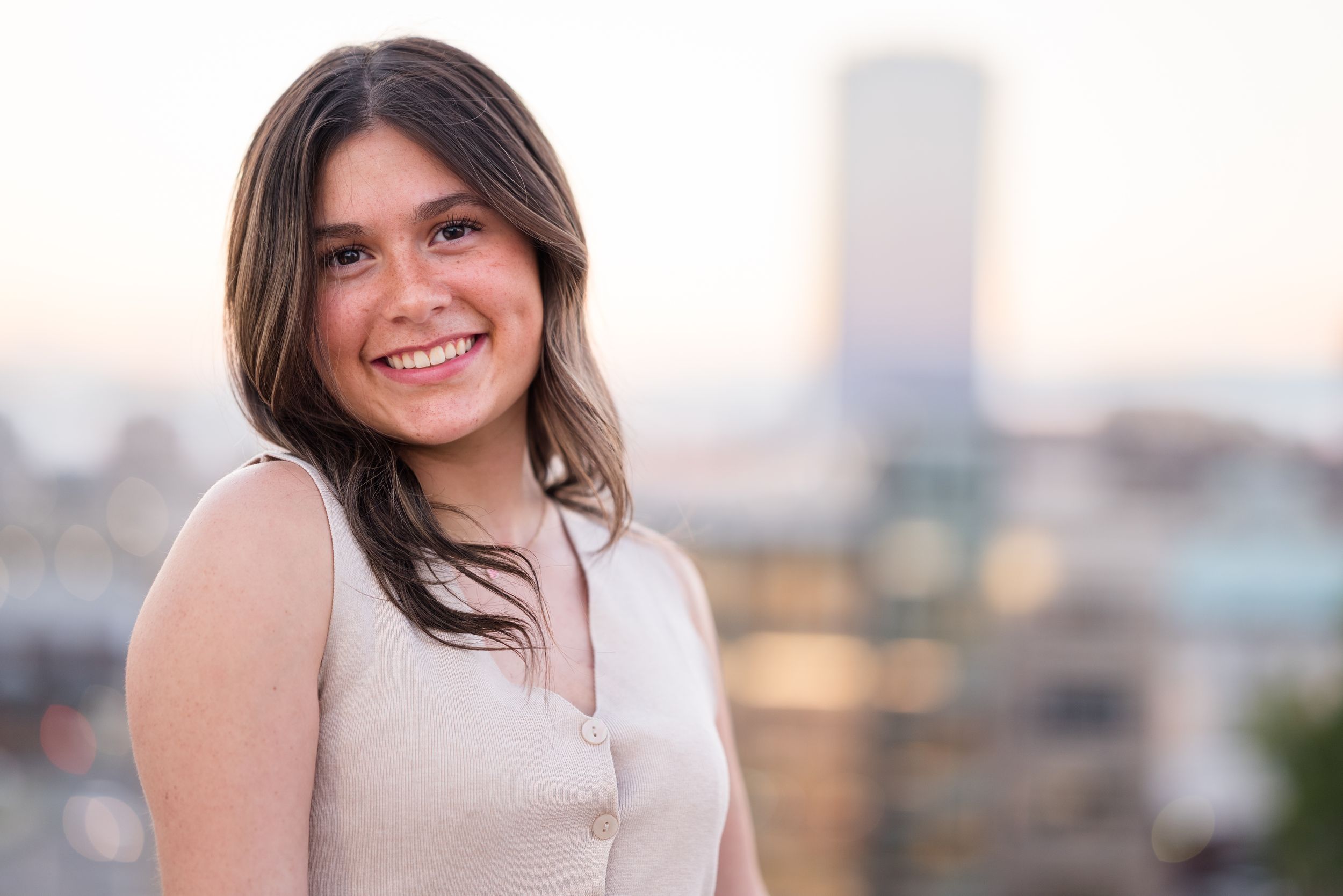 Outdoor portrait with city skyline visible in background during golden hour lighting.