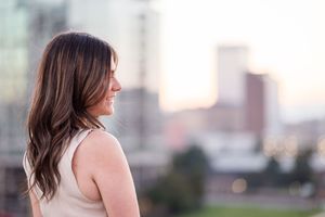 Side profile view on a rooftop with city buildings visible in the sunset background.