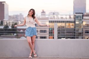 Casual summer outfit pose on urban rooftop with cityscape and buildings in background at dusk.
