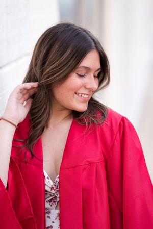 Fashion model wearing bright red blazer and floral top poses playfully in studio setting.