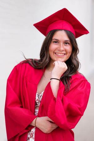 Playful graduation photos in bright red academic regalia against white backdrop.