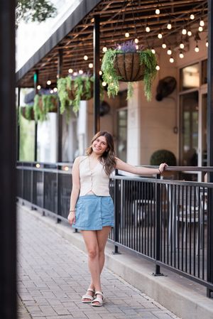 Outdoor portrait session along a covered walkway with string lights and black railings.