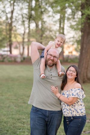 A couple in casual outfits laughing and embracing outdoors in a park setting during golden hour.
