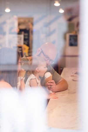 A couple sharing an intimate moment while eating ice cream cones together at a white counter.