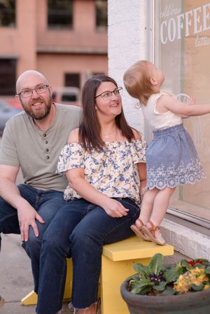 A couple sits together on a yellow bench outside a coffee shop, sharing a lighthearted moment.