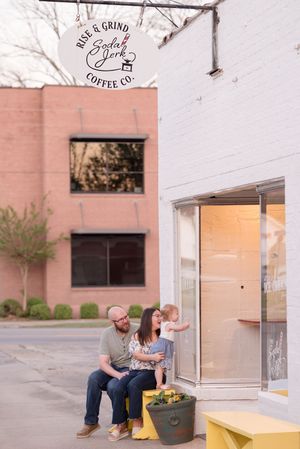 Urban family photo session outside a modern building with pink walls and yellow benches.